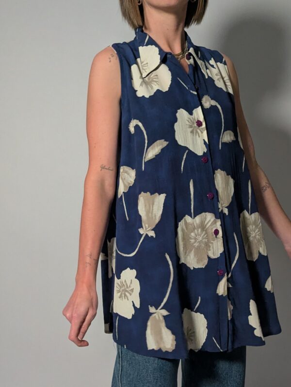 Vintage lange mouwloze blouse in diepblauw met grote bloemenprint in crème en opvallende paarse knopen.