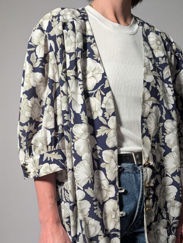 Vintage openvallend jasje in diepblauw met grote bloemenprint in crème en grijsgroene tinten.