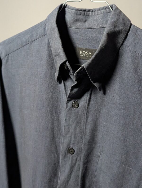 Vintage Hugo Boss blouse in blauwgrijze tint met lange mouwen, borstzak en relaxte pasvorm.