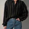Vintage zwarte blouse met lange mouwen en subtiele verticale strepen in een fijn contrasterend patroon.