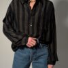 Vintage zwarte blouse met lange mouwen en subtiele verticale strepen in een fijn contrasterend patroon.