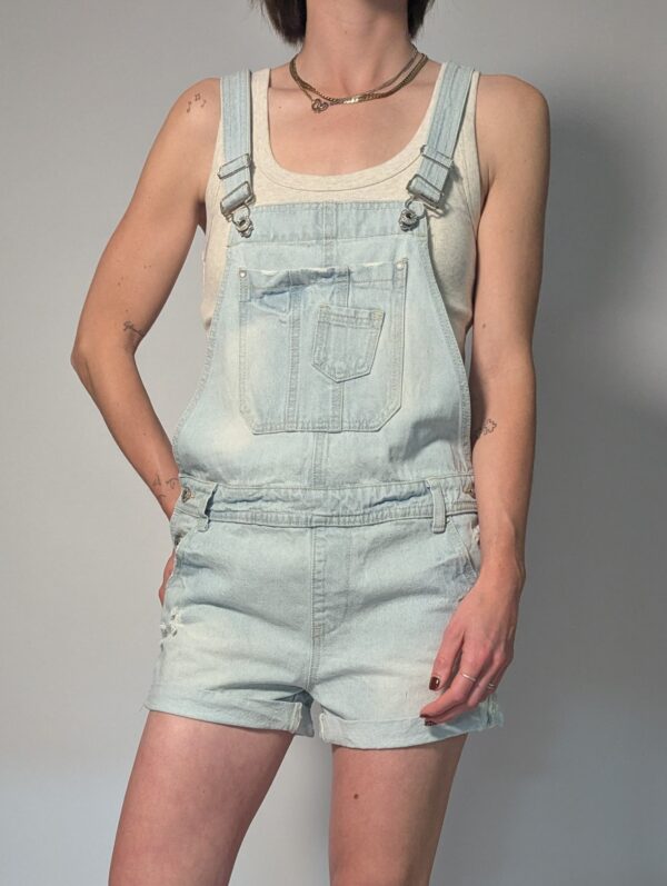 Vintage lichtblauwe denim playsuit met verstelbare schouderbanden, korte broekspijpen en relaxte pasvorm.