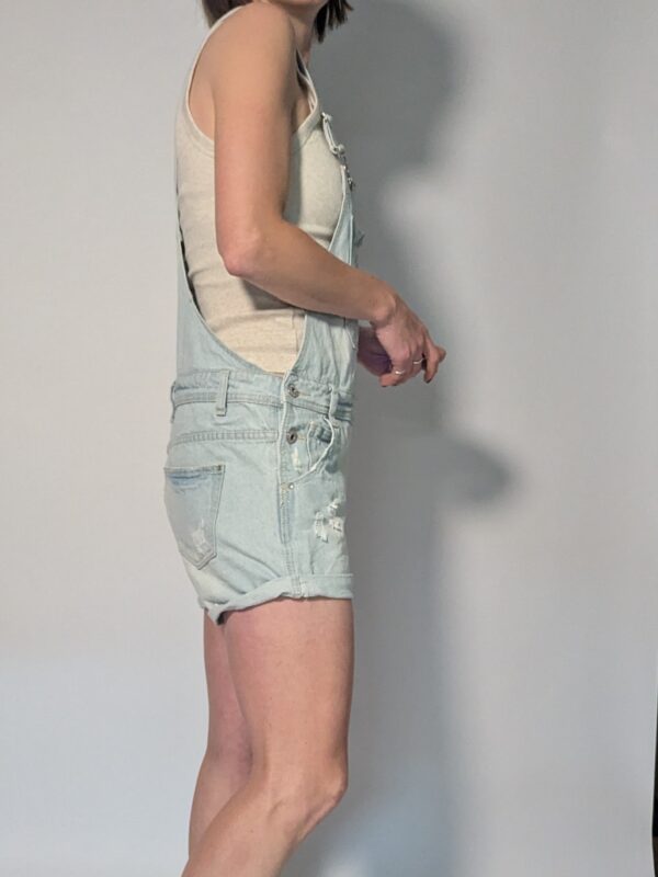 Vintage lichtblauwe denim playsuit met verstelbare schouderbanden, korte broekspijpen en relaxte pasvorm.