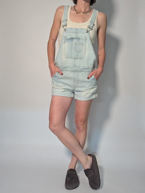 Vintage lichtblauwe denim playsuit met verstelbare schouderbanden, korte broekspijpen en relaxte pasvorm.