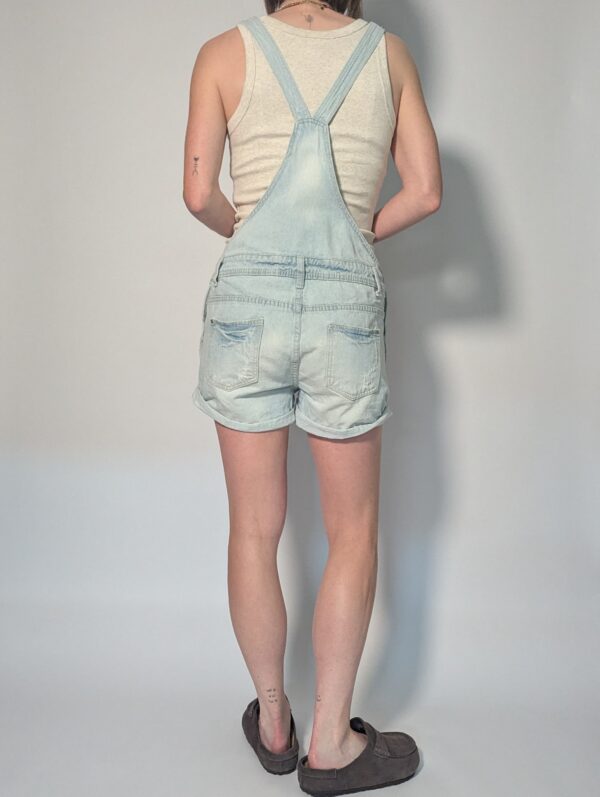 Vintage lichtblauwe denim playsuit met verstelbare schouderbanden, korte broekspijpen en relaxte pasvorm.
