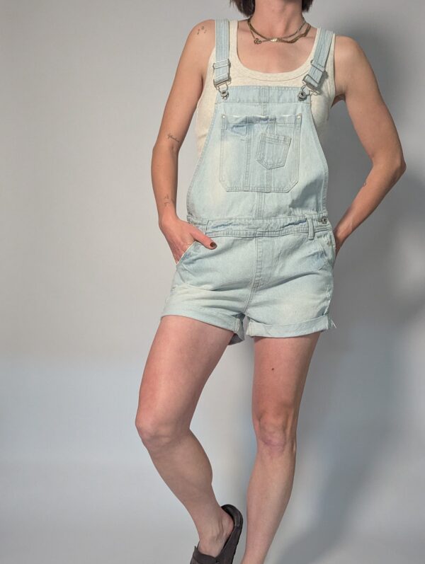 Vintage lichtblauwe denim playsuit met verstelbare schouderbanden, korte broekspijpen en relaxte pasvorm.