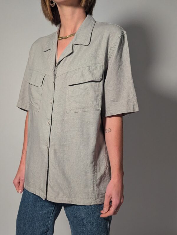 Vintage lichtgrijze blouse van 100% linnen met korte mouwen, relaxte pasvorm en dubbele borstzakken.
