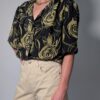 Vintage zwarte blouse met korte mouwen en abstracte rozenprint in olijfgroene tinten.
