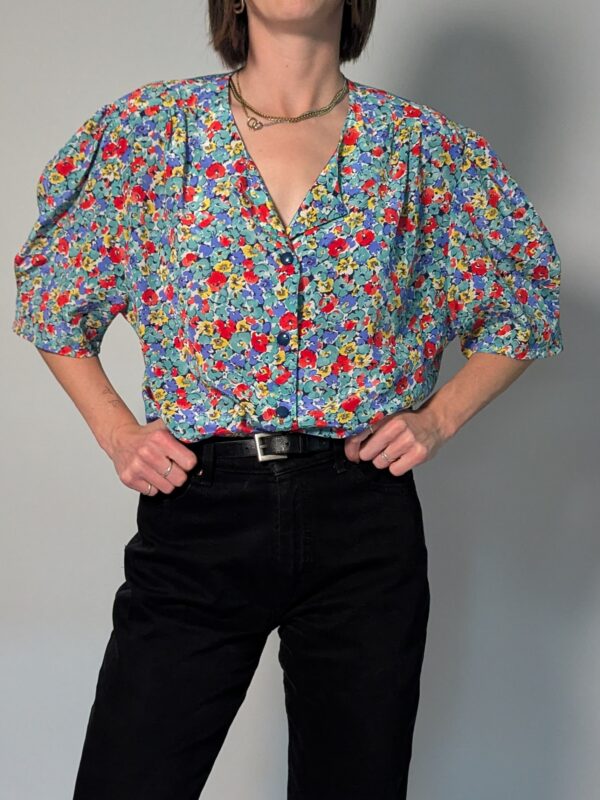 Vintage blouse met korte pofmouwen en kleurrijke bloemenprint in blauw, rood, geel en groentinten.