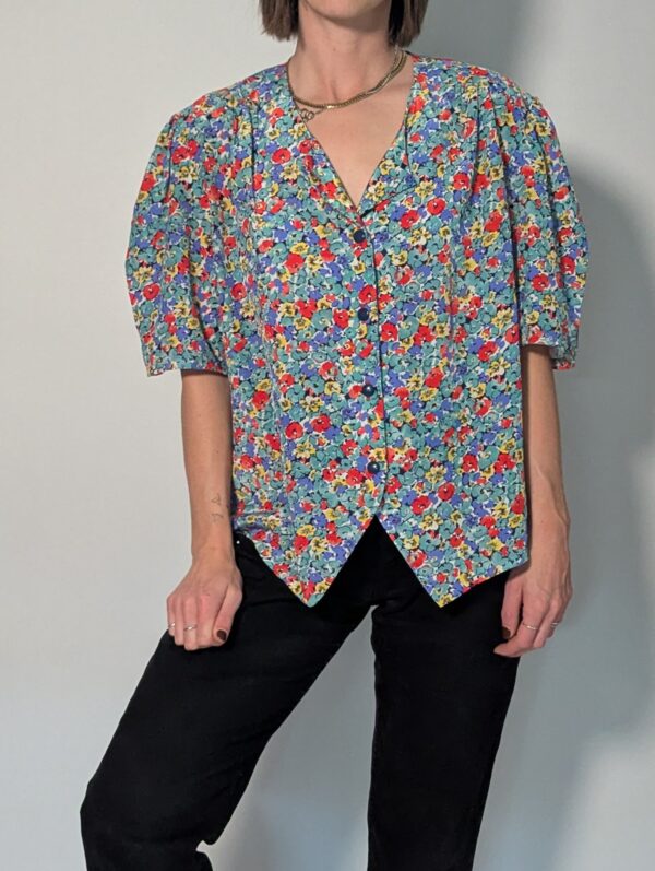 Vintage blouse met korte pofmouwen en kleurrijke bloemenprint in blauw, rood, geel en groentinten.