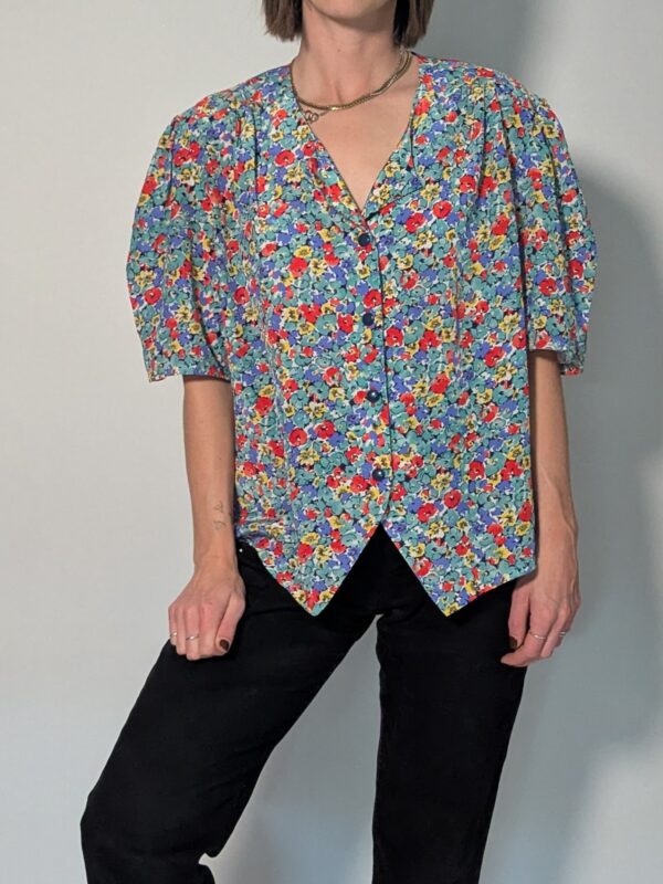 Vintage blouse met korte pofmouwen en kleurrijke bloemenprint in blauw, rood, geel en groentinten.