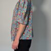 Vintage blouse met korte pofmouwen en kleurrijke bloemenprint in blauw, rood, geel en groentinten.