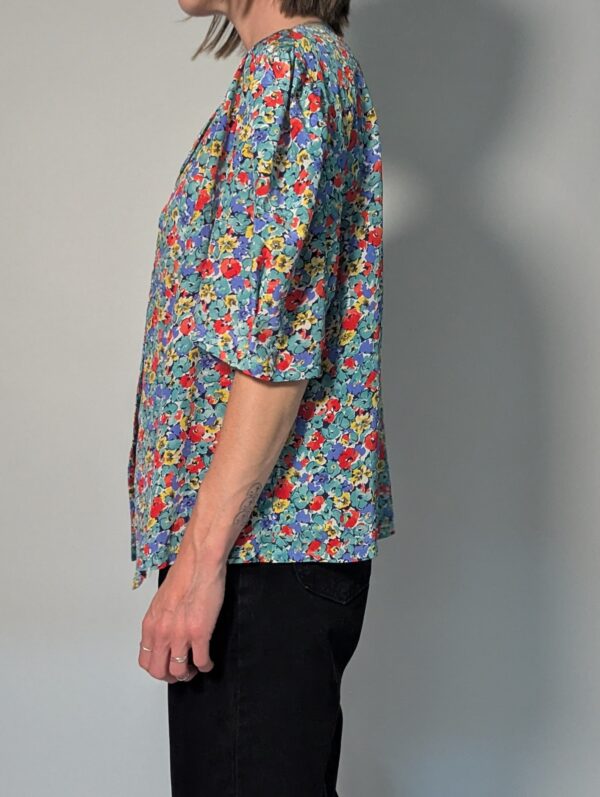 Vintage blouse met korte pofmouwen en kleurrijke bloemenprint in blauw, rood, geel en groentinten.