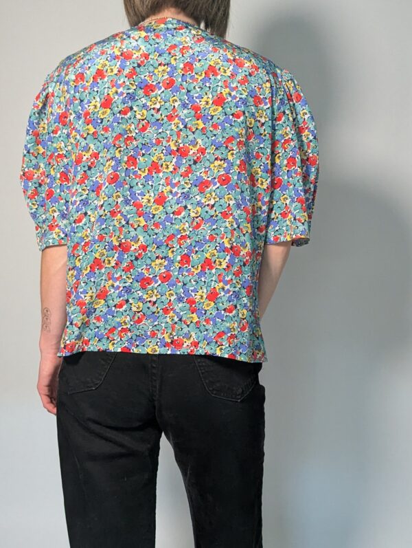 Vintage blouse met korte pofmouwen en kleurrijke bloemenprint in blauw, rood, geel en groentinten.