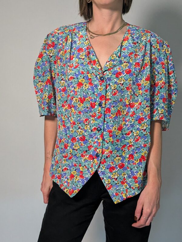 Vintage blouse met korte pofmouwen en kleurrijke bloemenprint in blauw, rood, geel en groentinten.