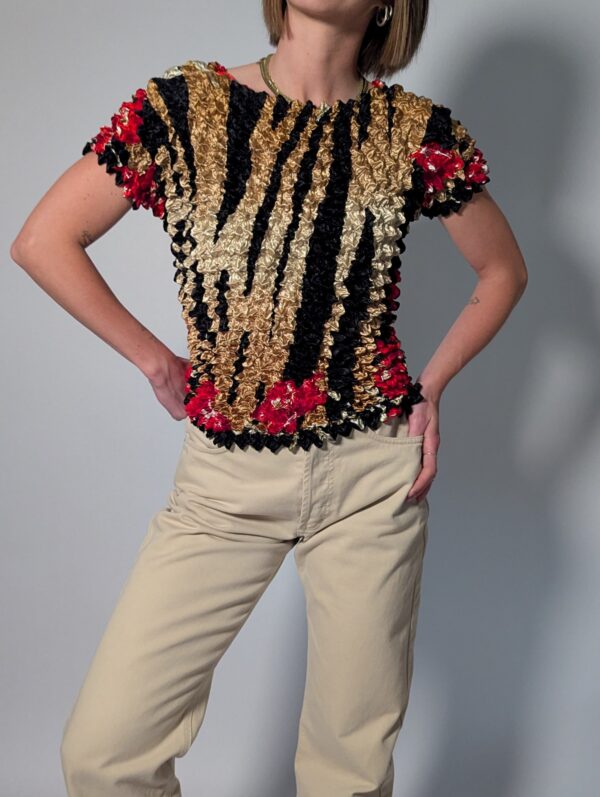 Vintage popcorn top in goud, zwart en rood met geplooide stretchstructuur en korte mouwen.