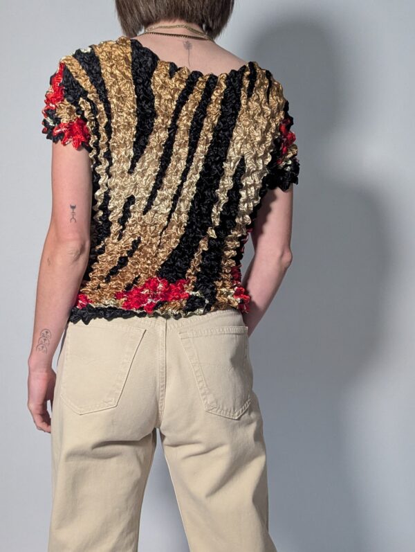 Vintage popcorn top in goud, zwart en rood met geplooide stretchstructuur en korte mouwen.