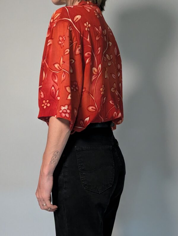Vintage roestrode blouse met korte mouwen en fijne florale print in zachte perzik- en zandtinten.
