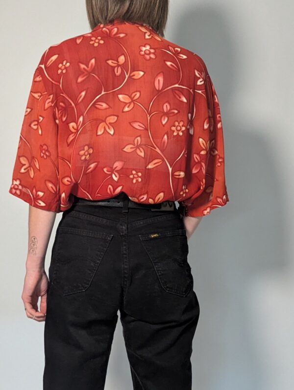 Vintage roestrode blouse met korte mouwen en fijne florale print in zachte perzik- en zandtinten.