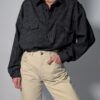 Vintage zwarte blouse met fijne verticale streep, lange mouwen en dubbele borstzakken.