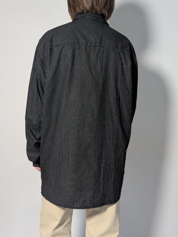 Vintage zwarte blouse met fijne verticale streep, lange mouwen en dubbele borstzakken.