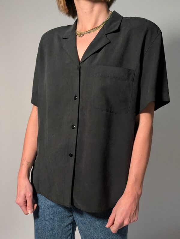 Vintage donkergrijze/zwarte blouse van 100% zijde met korte mouwen, borstzak en relaxte pasvorm.