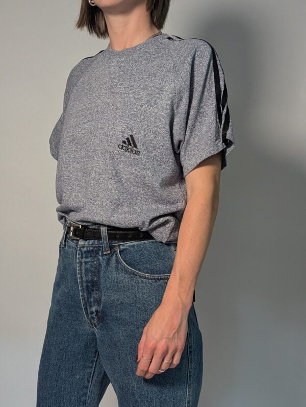 Sporty grey 03 Vintage Adidas T-shirt in gemêleerd grijs met korte mouwen, zwarte schouderstrepen en subtiel logo op de borst.