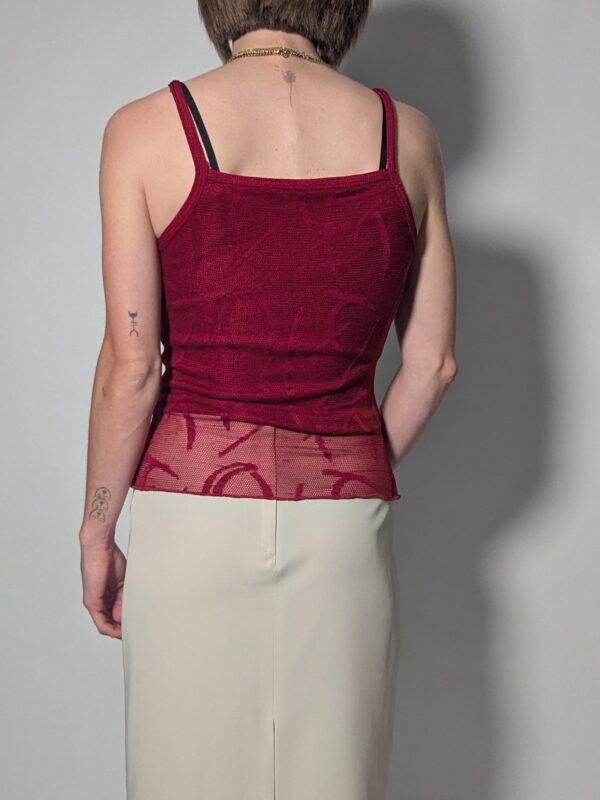 Vintage top in diepe bessentint met smalle schouderbandjes, aangesloten pasvorm en transparant mesh detail aan de onderzijde.