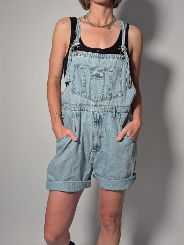 Denim overall 01 Vintage lichtblauwe denim overall met korte broekspijpen, verstelbare schouderbanden en relaxte pasvorm.