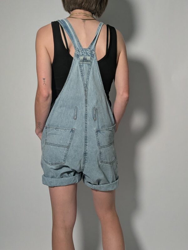 Denim overall 03 Vintage lichtblauwe denim overall met korte broekspijpen, verstelbare schouderbanden en relaxte pasvorm.