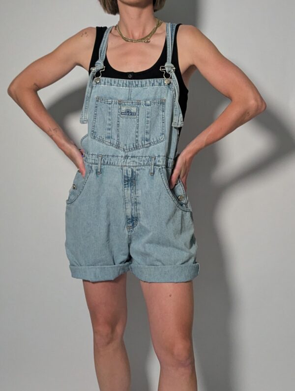 Denim overall 06 Vintage lichtblauwe denim overall met korte broekspijpen, verstelbare schouderbanden en relaxte pasvorm.