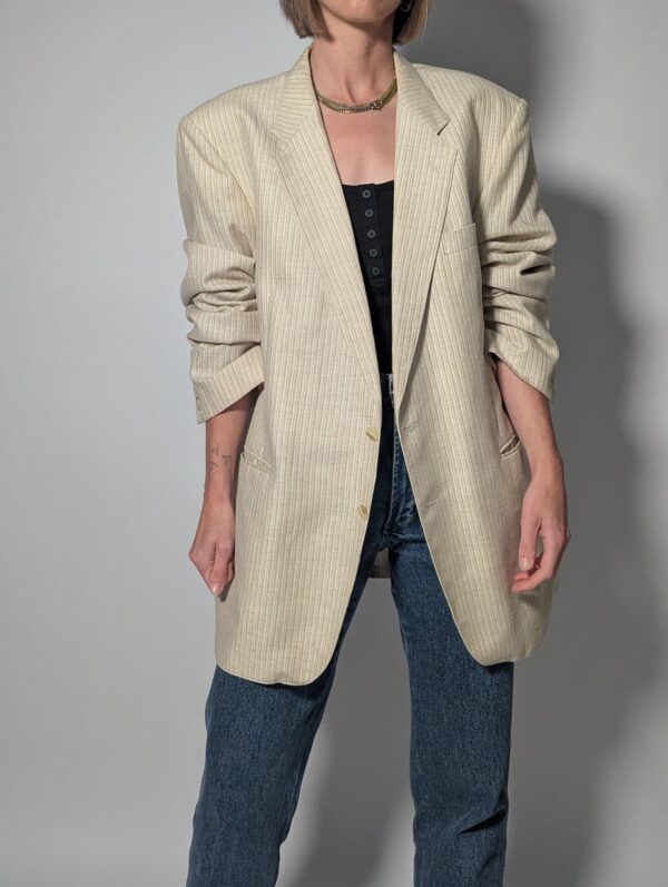 Vintage blazer in zachte ivoor- en beigetint met fijne krijtstreep, klassieke revers en rechte licht oversized pasvorm.