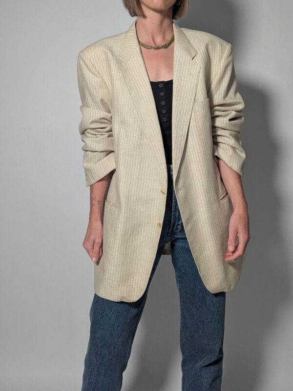 Vintage blazer in zachte ivoor- en beigetint met fijne krijtstreep, klassieke revers en rechte licht oversized pasvorm.