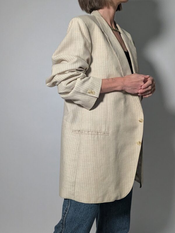 Vintage blazer in zachte ivoor- en beigetint met fijne krijtstreep, klassieke revers en rechte licht oversized pasvorm.