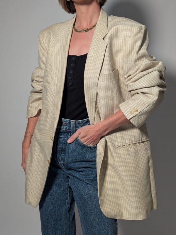 Vintage blazer in zachte ivoor- en beigetint met fijne krijtstreep, klassieke revers en rechte licht oversized pasvorm.