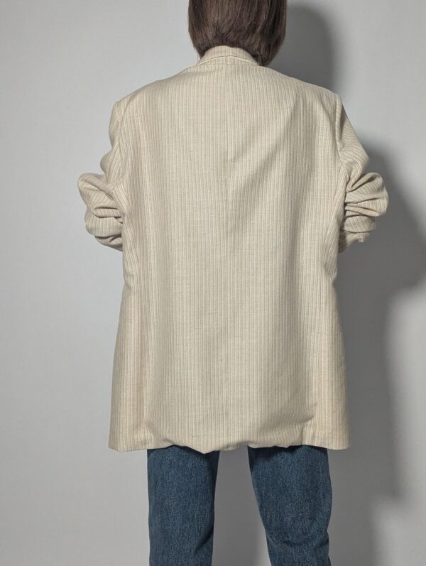 Vintage blazer in zachte ivoor- en beigetint met fijne krijtstreep, klassieke revers en rechte licht oversized pasvorm.