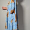 Vintage lichtblauwe blousejurk met grote bloemenprint in zand-, oker- en rozetinten, korte mouwen en knoopsluiting.