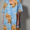 Vintage lichtblauwe blousejurk met grote bloemenprint in zand-, oker- en rozetinten, korte mouwen en knoopsluiting.