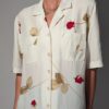 Vintage off-white blouse met korte mouwen, rode rozenprint en opgestikte borstzakken.