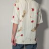 Vintage off-white blouse met korte mouwen, rode rozenprint en opgestikte borstzakken.