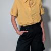 Sunlit pleat 01 Vintage lichtoranje blouse met korte mouwen, plooidetails aan de voorkant en opgerolde mouwen met tab detail.