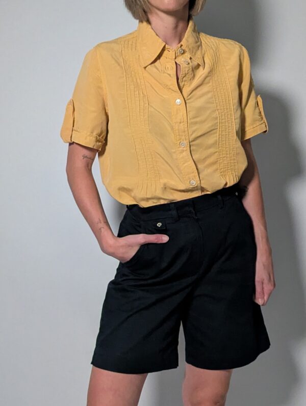 Sunlit pleat 01 Vintage lichtoranje blouse met korte mouwen, plooidetails aan de voorkant en opgerolde mouwen met tab detail.