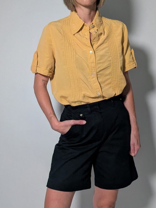 Sunlit pleat 01 Vintage lichtoranje blouse met korte mouwen, plooidetails aan de voorkant en opgerolde mouwen met tab detail.
