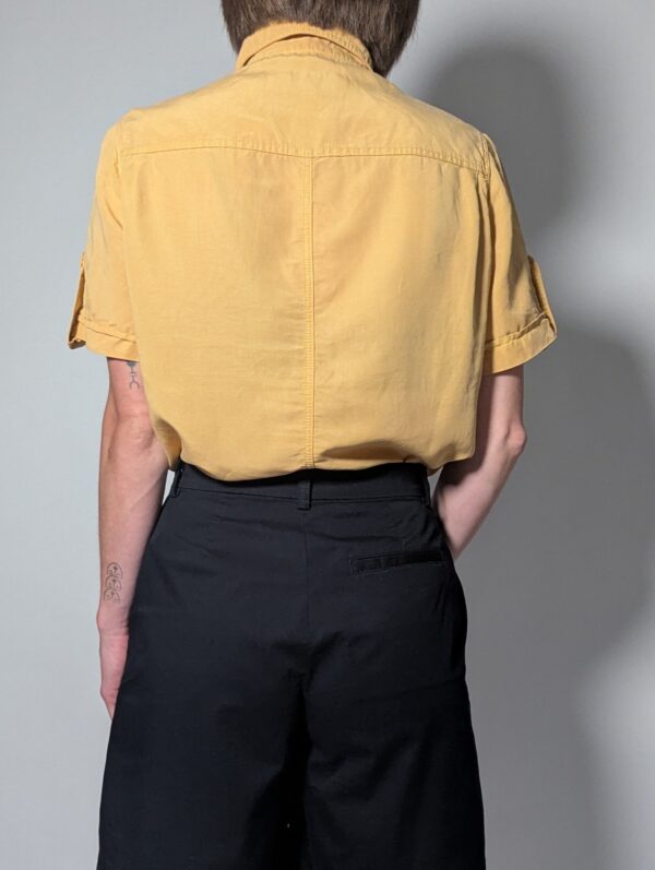 Sunlit pleat 02 Vintage lichtoranje blouse met korte mouwen, plooidetails aan de voorkant en opgerolde mouwen met tab detail.