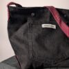(RE)MADE BY LOT zwarte denim tas met schuine pocket en hengsels gemaakt van een hergebruikte bordeauxrode stropdas.