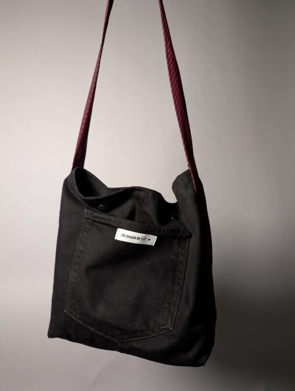 (RE)MADE BY LOT zwarte denim tas met schuine pocket en hengsels gemaakt van een hergebruikte bordeauxrode stropdas.