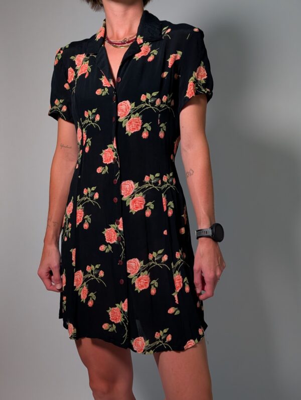 Vintage donkerblauwe jurk met korte pofmouwen, knoopsluiting en rozenprint in rood- en groentinten.