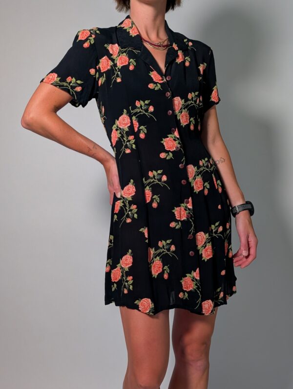 Vintage donkerblauwe jurk met korte pofmouwen, knoopsluiting en rozenprint in rood- en groentinten.