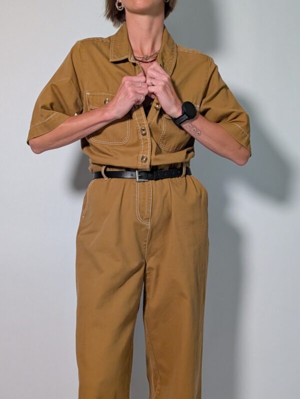 Ochre utility 02 Vintage okerbruine utility jumpsuit met korte mouwen, contrasterende stiksels, borstzakken en wijde pijpen.