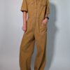 Ochre utility 03 Vintage okerbruine utility jumpsuit met korte mouwen, contrasterende stiksels, borstzakken en wijde pijpen.